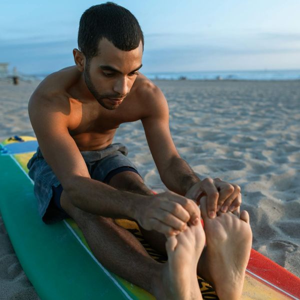 Man performing a powerful yoga warrior pose outdoors at sunset.